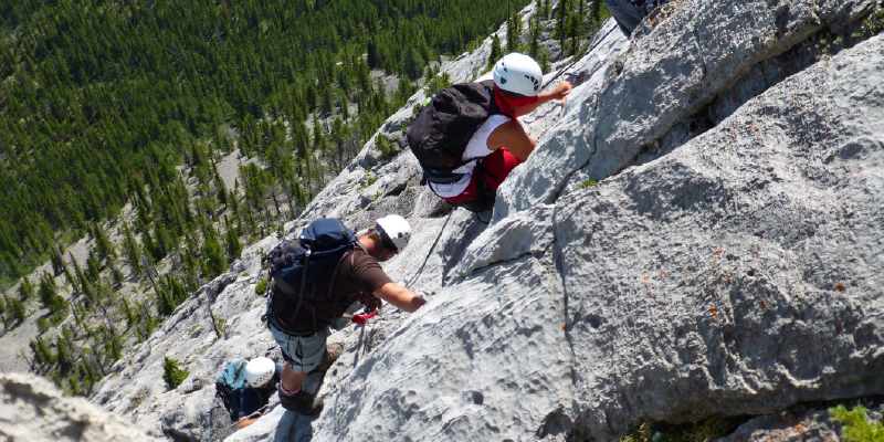 A line of hikers climbing up a steep rock mountain