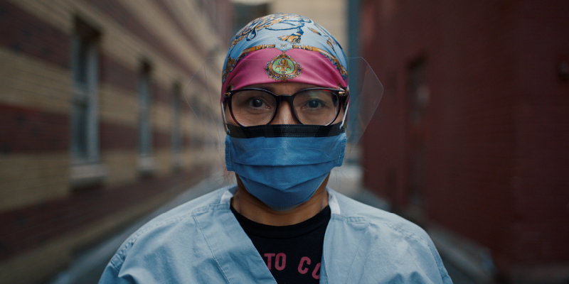 A women in scrubs and a face mask and glasses