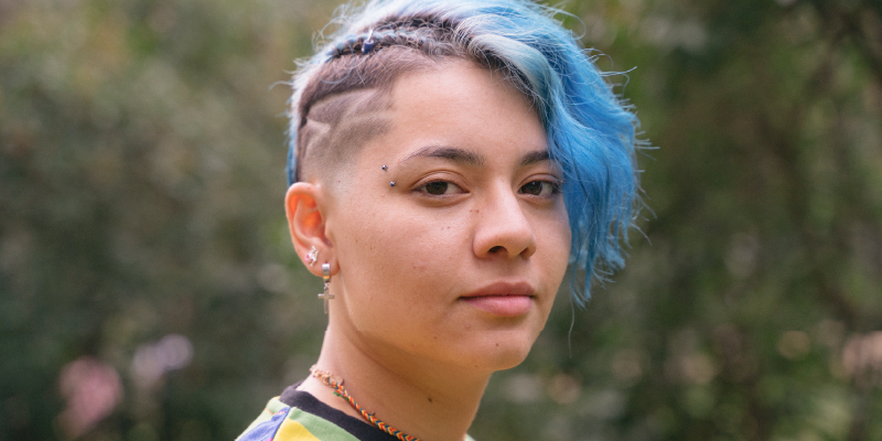 Young cheerful woman with expression of sadness and blue short hair.